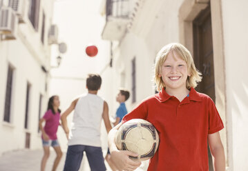 Junge hält Fußball in Gasse - CAIF19795