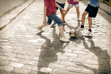 Kinder spielen mit Fußball auf einer Straße mit Kopfsteinpflaster - CAIF19801