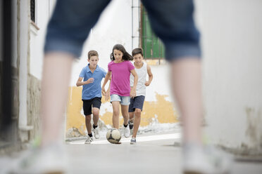 Children playing with soccer ball in alley - CAIF19803