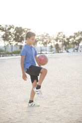 Junge kniet mit Fußball im Sand - CAIF19804