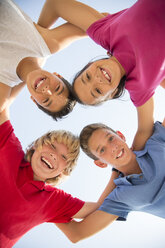 Low angle view of children smiling in huddle - CAIF19805