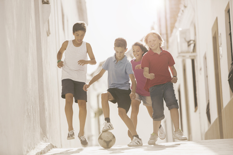 Kinder spielen mit Fußball in der Gasse, lizenzfreies Stockfoto