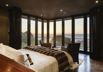 Luxury bedroom overlooking ocean at sunset - CAIF19884