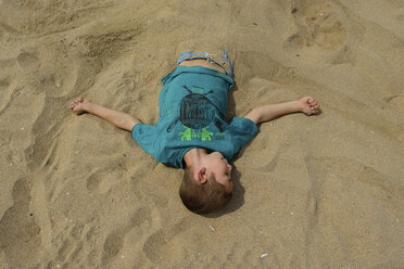High angle view of boy buried in sand at beach - CAVF10403