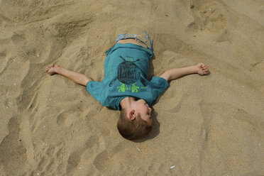 Hoher Blickwinkel auf einen im Sand vergrabenen Jungen am Strand - CAVF10403