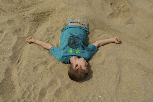 Hoher Blickwinkel auf einen im Sand vergrabenen Jungen am Strand - CAVF10403