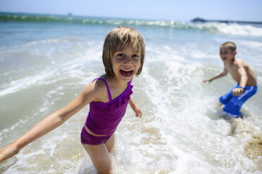 Portrait of happy girl playing with brother in sea at Oceanside beach - CAVF10405