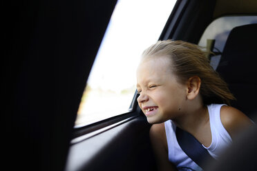 Girl enjoying wind while sitting by window in car - CAVF10427