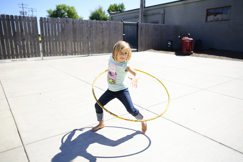 Porträt eines Mädchens, das auf einem Spielplatz im Sommer mit einem Hula-Hoop-Reifen spielt, lizenzfreies Stockfoto