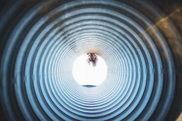 Playful girl peeking through tube at playground - CAVF10462