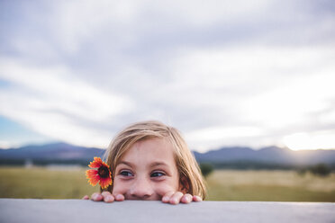 Girl peeking from retaining wall while wearing flower - CAVF10492