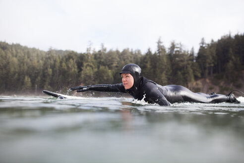 Seitenansicht einer Frau auf einem Surfbrett im Meer liegend - CAVF10545