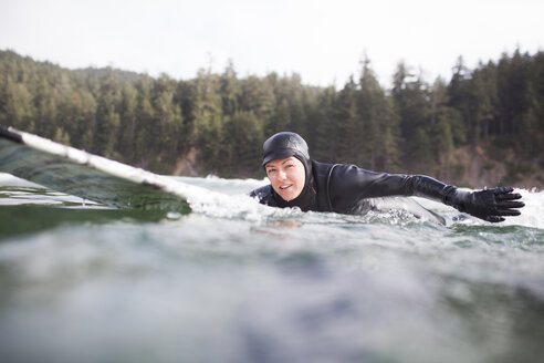 Porträt einer Frau auf einem Surfbrett im Meer liegend - CAVF10546