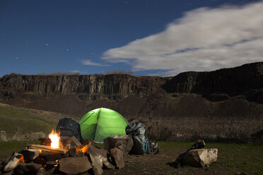 Campfire by tent against mountains during dusk - CAVF10583