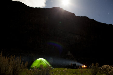 Campfire by tent against mountains during sunset - CAVF10584