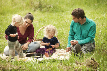 Family having food while sitting on grassy field - CAVF10602