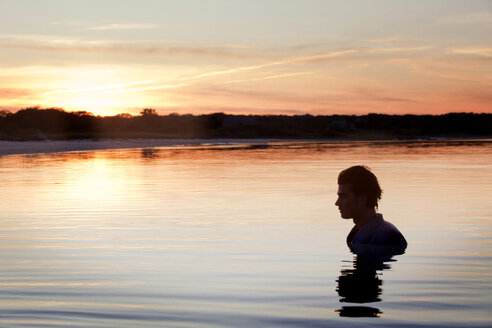 Mann schwimmt im See gegen den Himmel bei Sonnenuntergang - CAVF10643