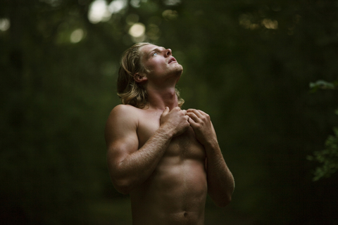 Scared man looking up in forest stock photo