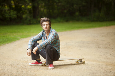 Porträt eines Mannes auf einem Longboard sitzend - CAVF10679