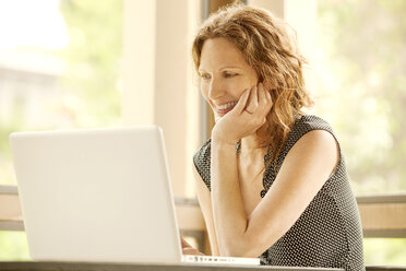 Happy woman using laptop computer at home - CAVF10702
