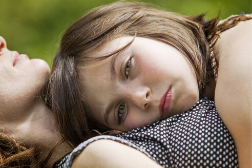 Porträt eines auf der Brust der Mutter liegenden Mädchens im Garten - CAVF10709