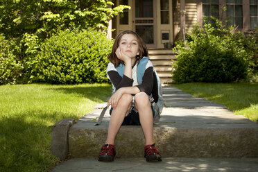 Portrait of girl with backpack sitting on footpath - CAVF10713