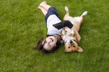 Porträt eines Mädchens, das mit einem Hund auf einem Feld im Hof spielt - CAVF10729