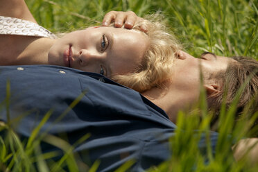 Porträt einer Frau, die sich an die Brust eines Mannes lehnt, während sie in einem Grasfeld liegt - CAVF10746