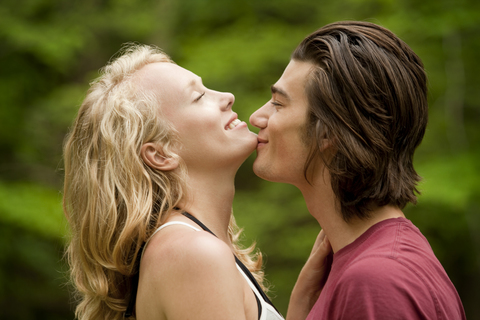 Mann küsst Freundin auf Kinn, lizenzfreies Stockfoto