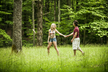 Paar hält Hände beim Spaziergang auf grasbewachsenen Feld - CAVF10751