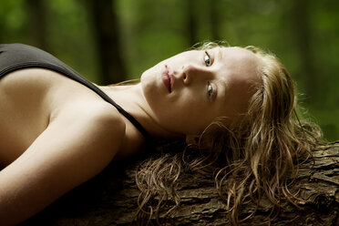 Portrait of sensual woman lying on tree trunk - CAVF10765
