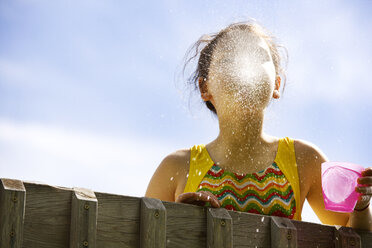 Low angle view of girl spitting water while standing against sky - CAVF10778