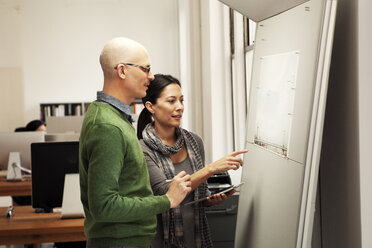 Geschäftskollegen betrachten ein Diagramm auf einer Tafel im Büro - CAVF10839