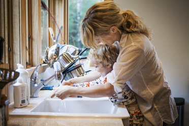 Mutter hilft ihrem Sohn beim Händewaschen an der Küchenspüle - CAVF10852