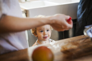 Boy looking at raspberry in kitchen - CAVF10859