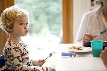 Cute boy holding fork while sitting at table - CAVF10876