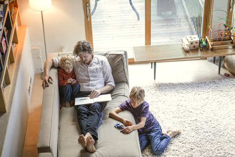 Blick von oben auf den Vater, der mit seinen Söhnen zu Hause sitzt, lizenzfreies Stockfoto