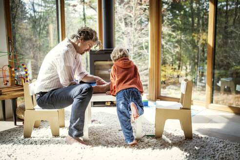 Vater bringt seinem Sohn das Schreiben bei, während er zu Hause auf einem Stuhl sitzt - CAVF10901