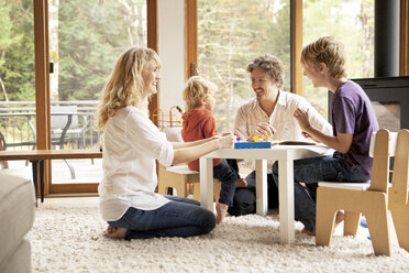 Cheerful siblings making craft with parents at home - CAVF10906