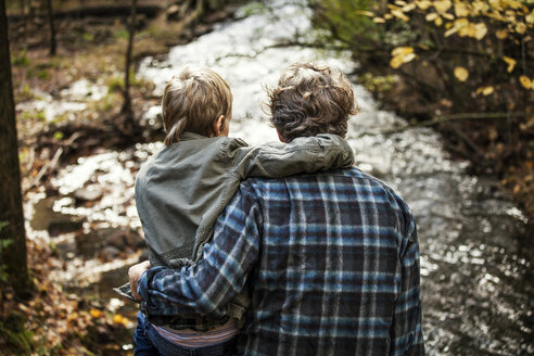 Rückansicht von Vater und Sohn, die am Fluss sitzen - CAVF10920