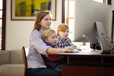 Mutter verwendet Desktop-Computer, während sie mit ihren Kindern zu Hause sitzt - CAVF10992