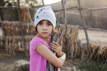 Portrait of girl holding woods at field - CAVF11001