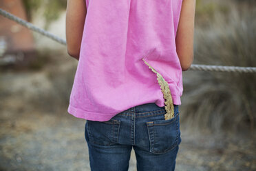 Rückansicht eines Mädchens mit Blatt in der Tasche auf einem Feld - CAVF11006