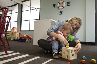 Woman and boy playing with geometric puzzle box at preschool - CAVF11033