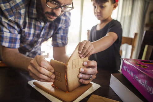 Vater und Sohn bauen zu Hause ein Pfefferkuchenhaus - CAVF11054