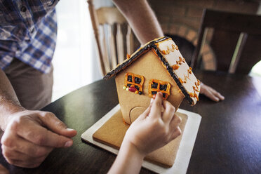 Ausgeschnittenes Bild eines Jungen, der zu Hause ein Lebkuchenhaus dekoriert - CAVF11059
