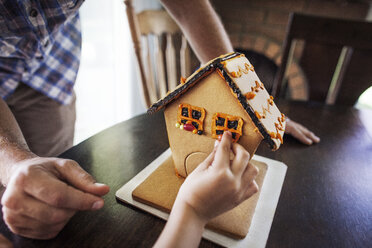 Cropped image of boy decorating gingerbread house at home - CAVF11059