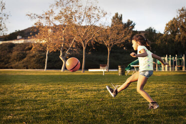 Girl kicking basketball while playing in court - CAVF11075