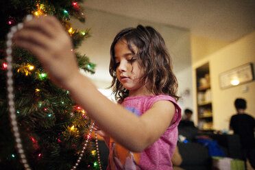 Mädchen schmückt Weihnachtsbaum zu Hause - CAVF11077