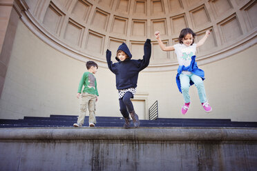 Low angle view of children jumping from staircase - CAVF11100